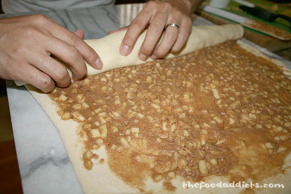 When the dough is ready, roll it out and spread the cinnamon mixture on top. Then, roll the dough into a log and pinch the dough together to seal at the end of the roll. 